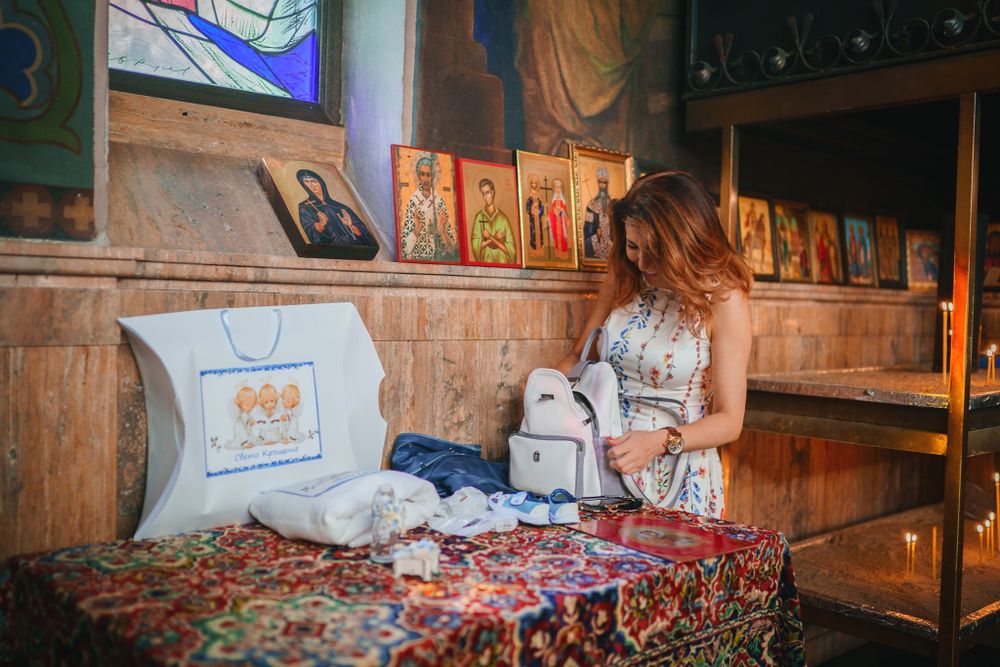 Religious items and icons displayed on decorated table inside church with wooden panels.
