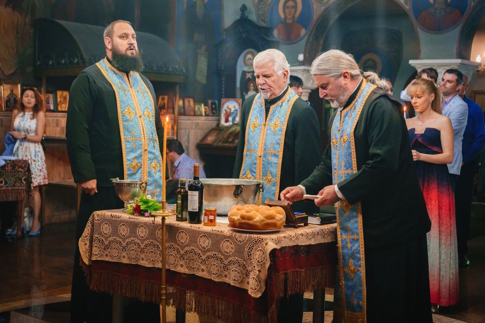 Orthodox priests performing a religious ceremony at an altar with candles and sacred items.