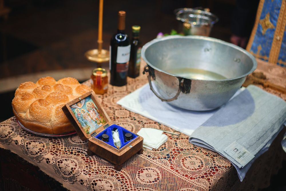 Religious ceremonial items including bread, holy water, and candles arranged on an ornate cloth.