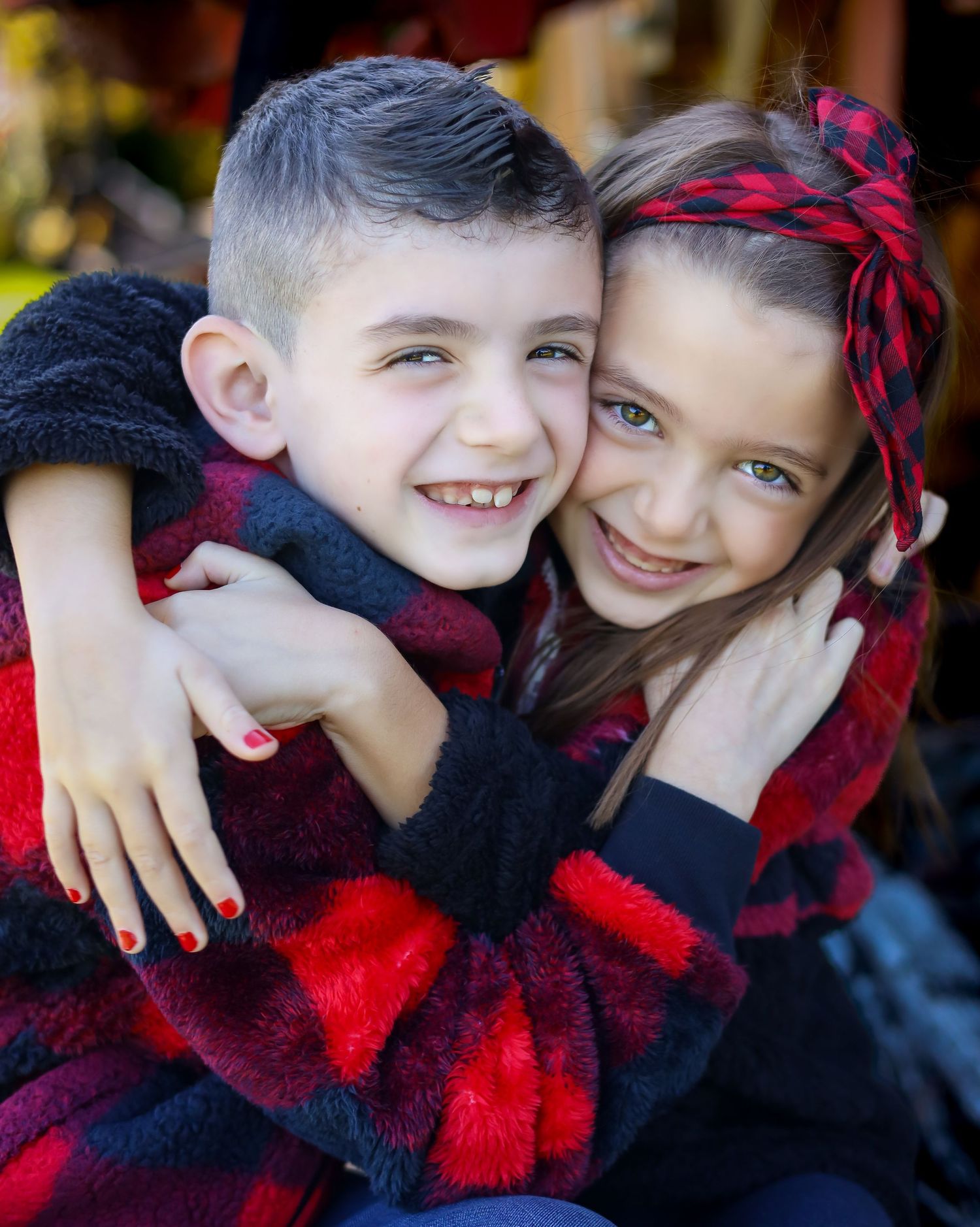 Children in buffalo plaid outfits sharing warm hugs and smiles.