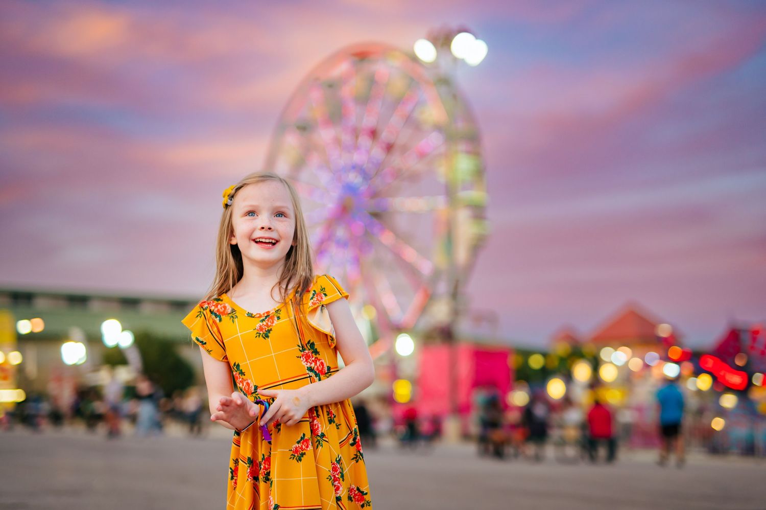 Tulsa State Fair child photographer with Ferris Wheel in the background with girl in yellow dress