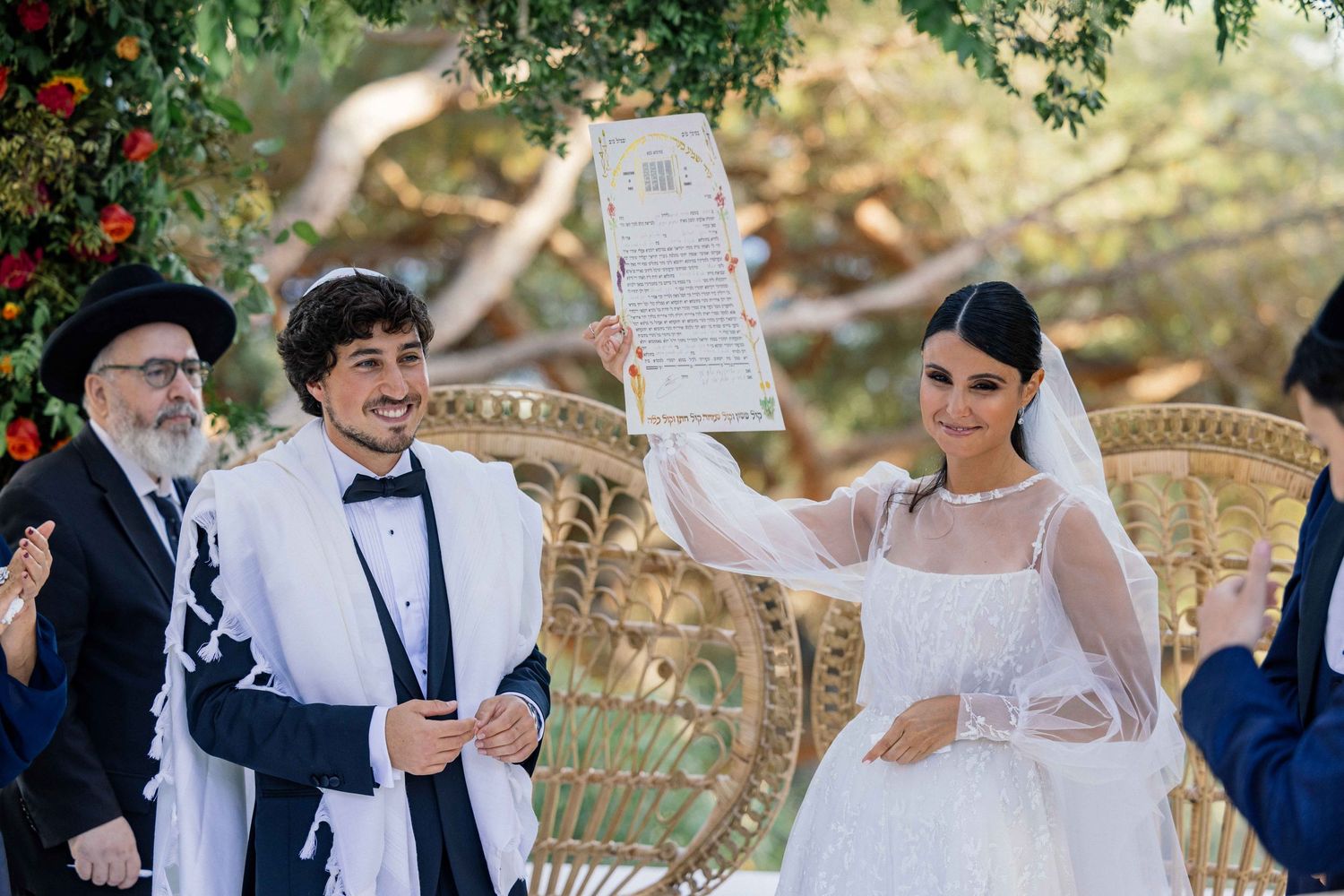 Wedding ceremony in a garden setting with attendees seated on ornate chairs.