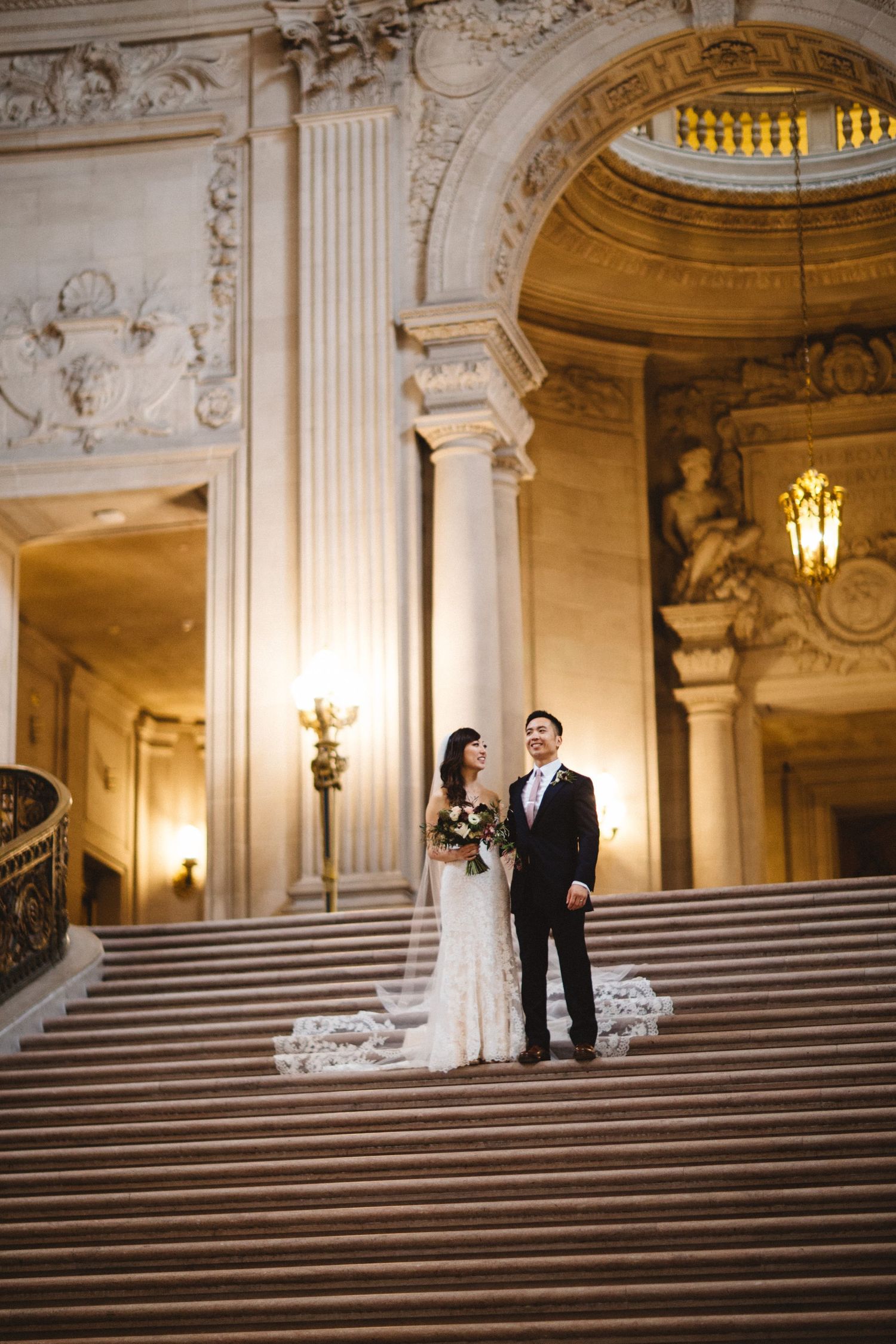 A wedding portrait on the grand staircase showcasing the ornate Beaux-Arts architecture.