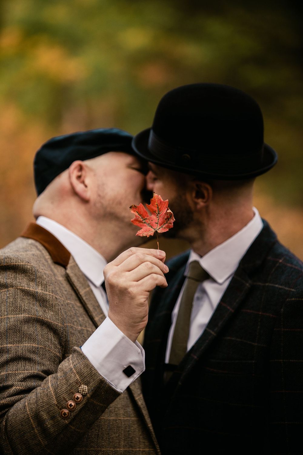 Intimate moment between couple sharing autumn leaf in forest setting.