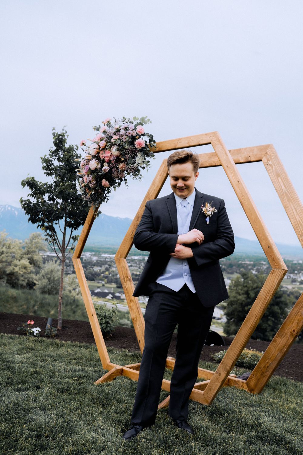 Geometric wooden hexagon arch with floral decorations against mountain landscape.