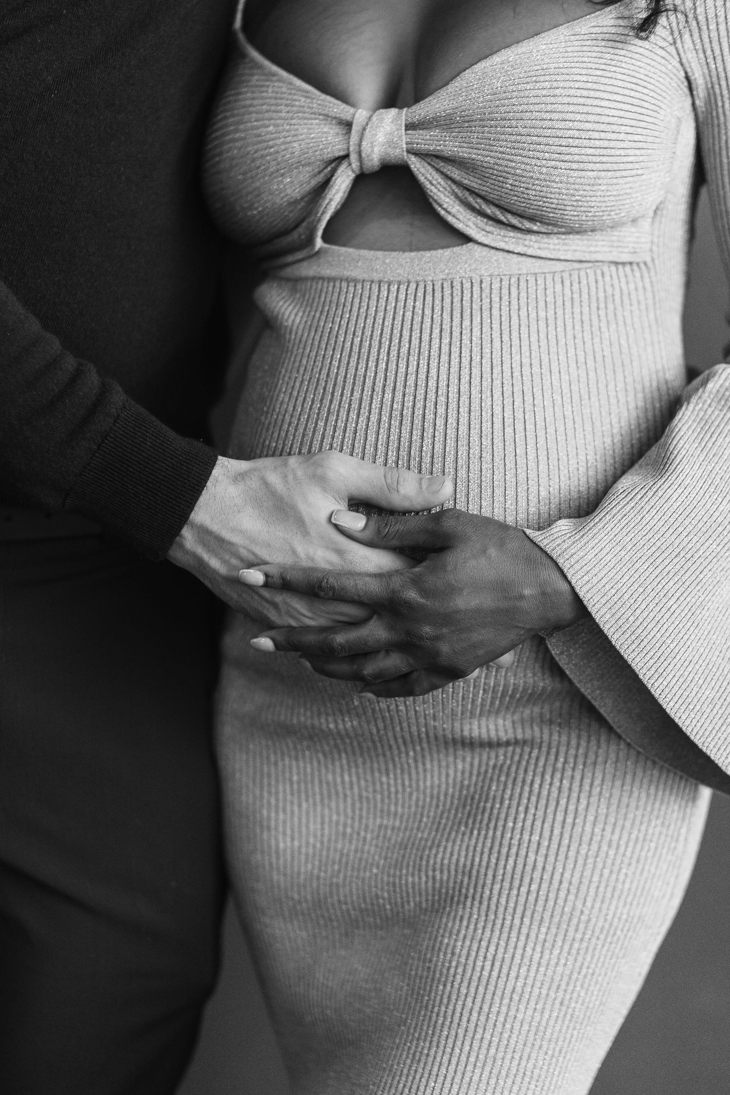a black and white close up detail of a couple holding their baby bump during their baby shower in Hoboken, NJ