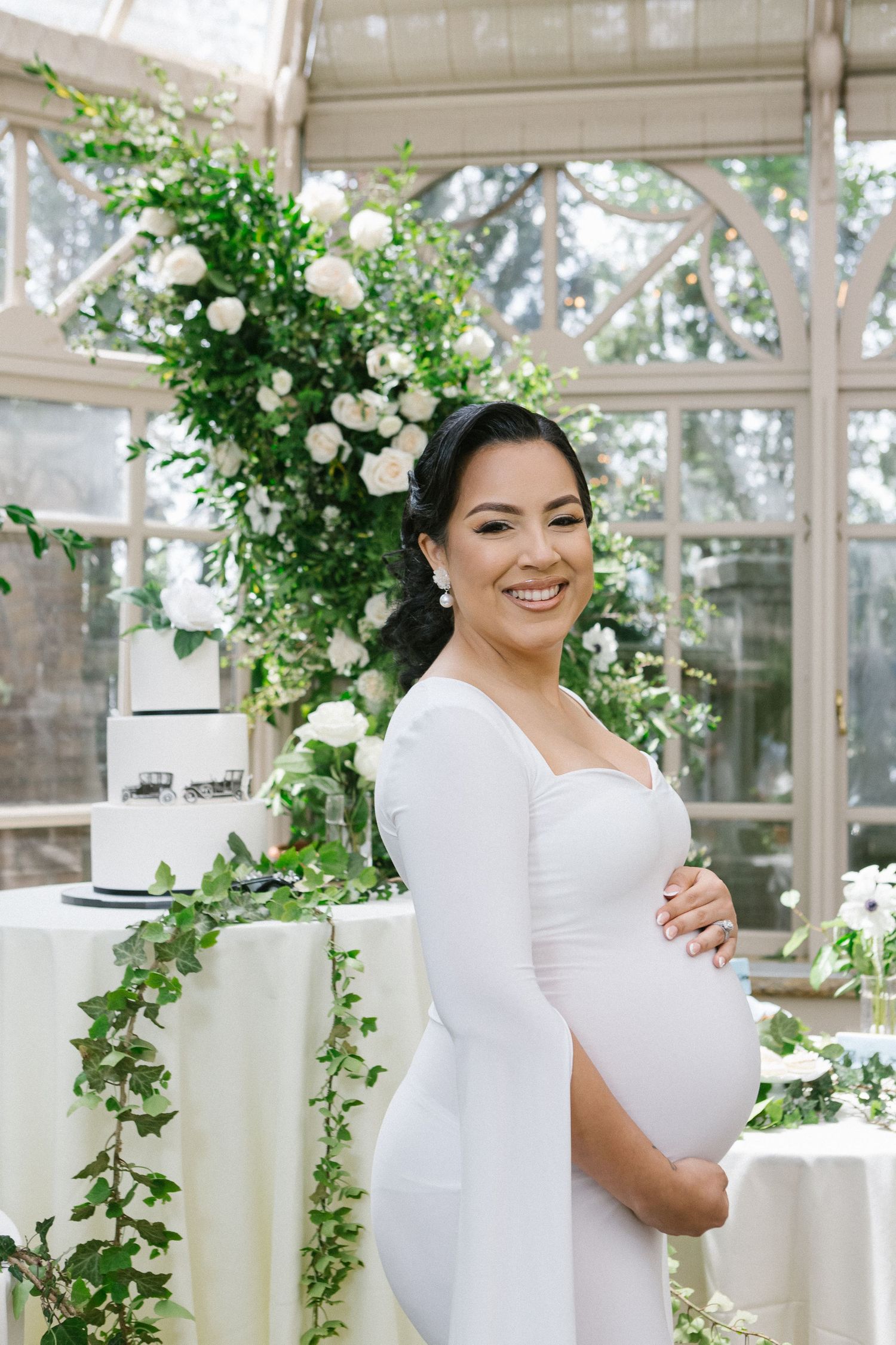 a half body profile view of a pregnant woman standing in front of baby shower decor by Paula Ortiz NY Family Photography