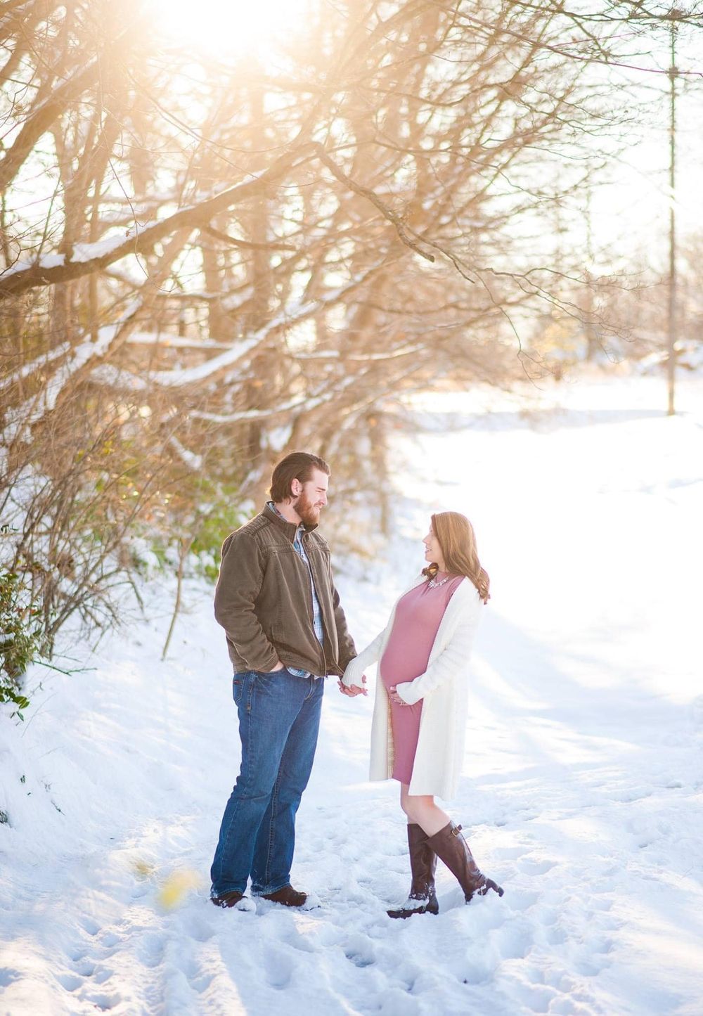 A couple stands together in deep snow during a bright winter day.