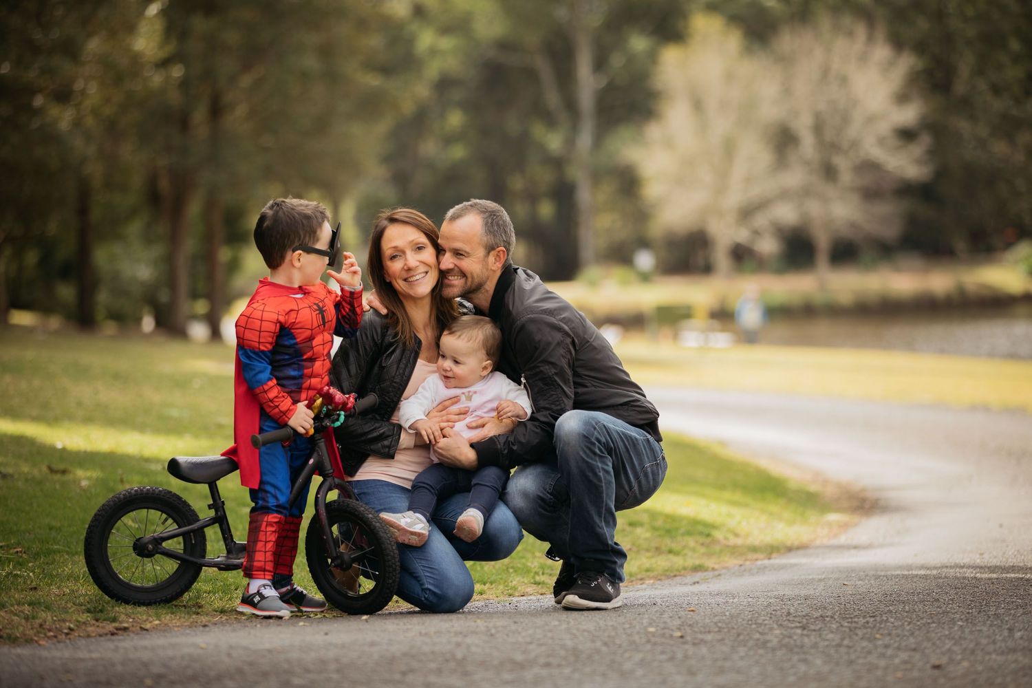Family photo in Fagan Park with boy on bike dressed as Superman
