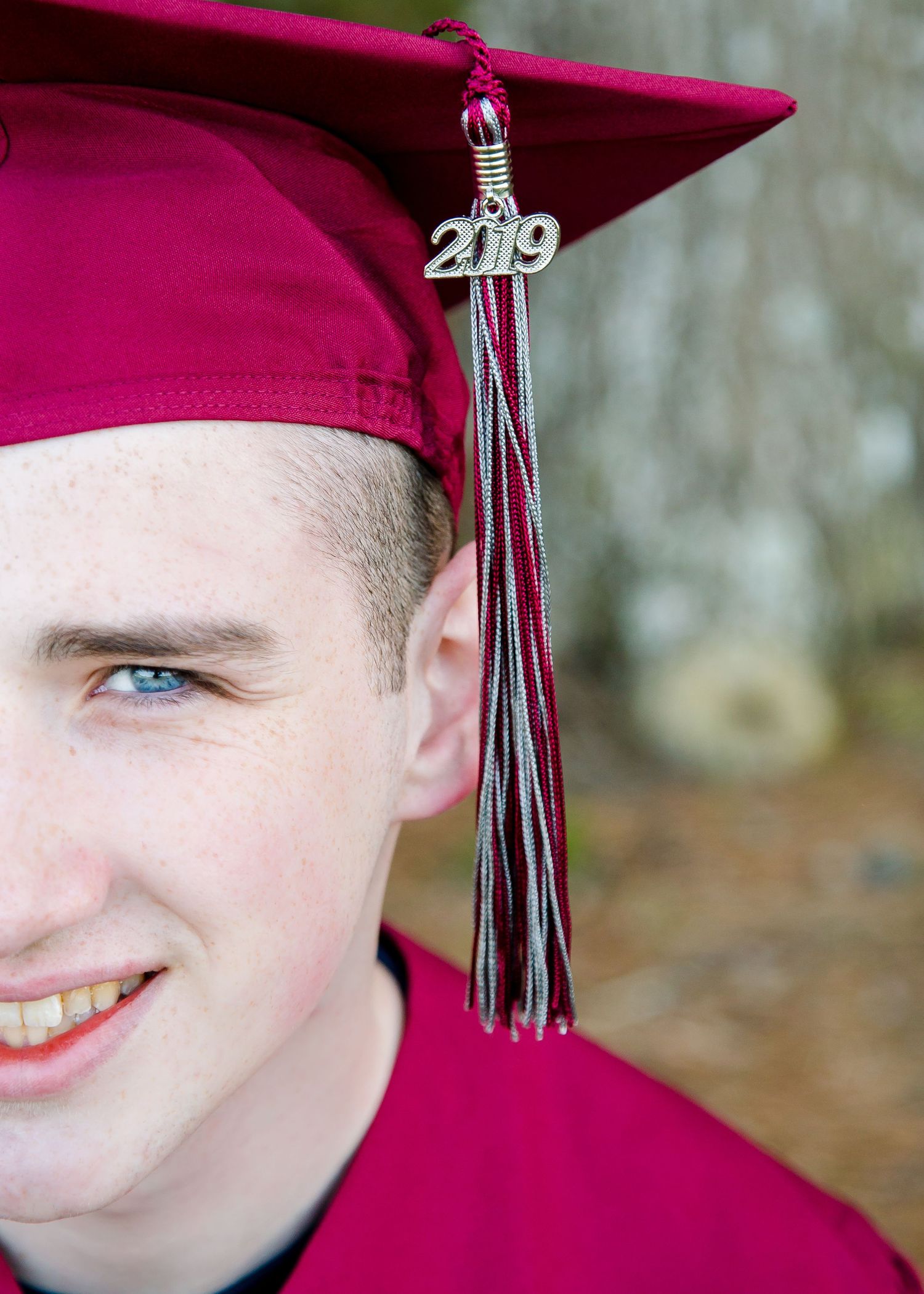Close-up of male graduate in burgundy cap with 2019 tassel charm.