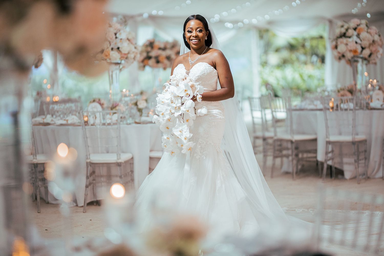 Wedding reception venue decorated with elegant white floral arrangements and candlelight.