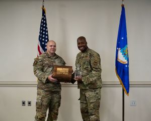 Military personnel holding a commemorative plaque during an award ceremony.