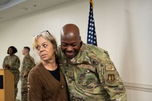 Military personnel in camouflage uniforms gather for a group meeting in an office setting.