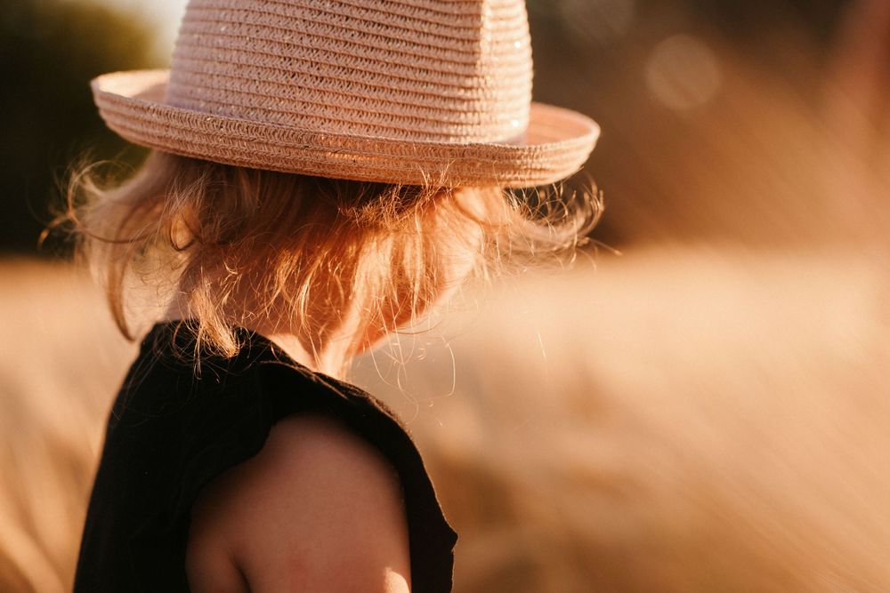 Person wearing a pink straw hat in warm sunset lighting.