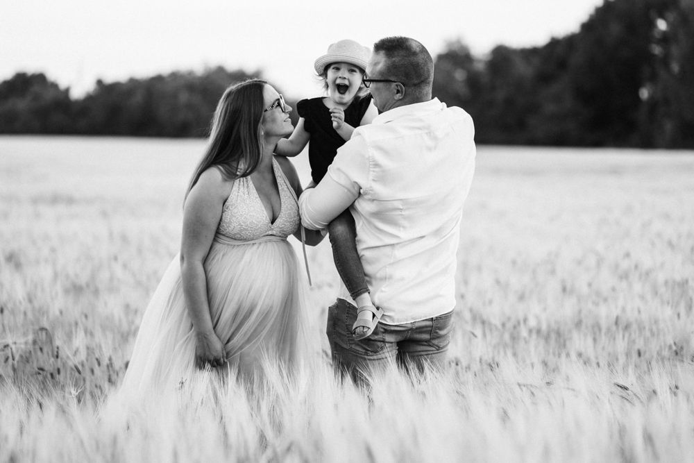 A tender maternity photoshoot in a golden wheat field captured in black and white.