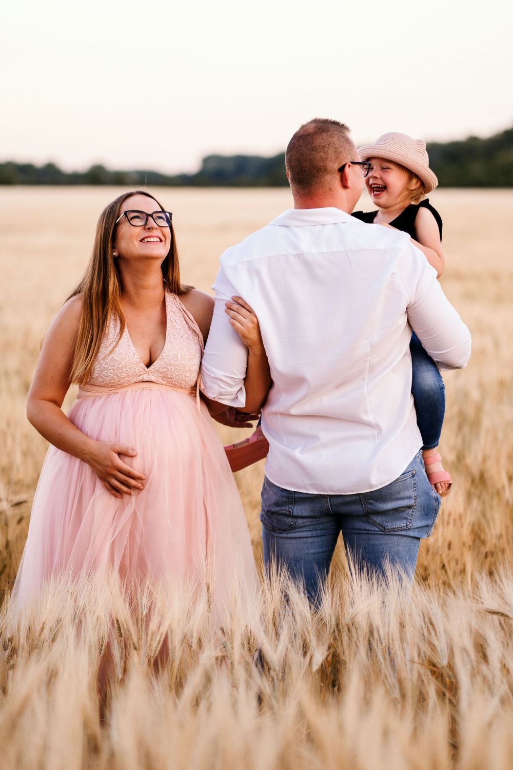 Joyful family moment captured in a wheat field during golden hour.
