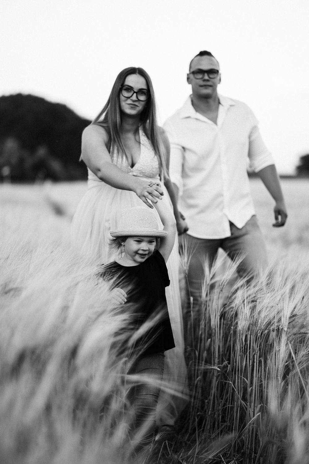 Black and white family portrait in wheat field at sunset.