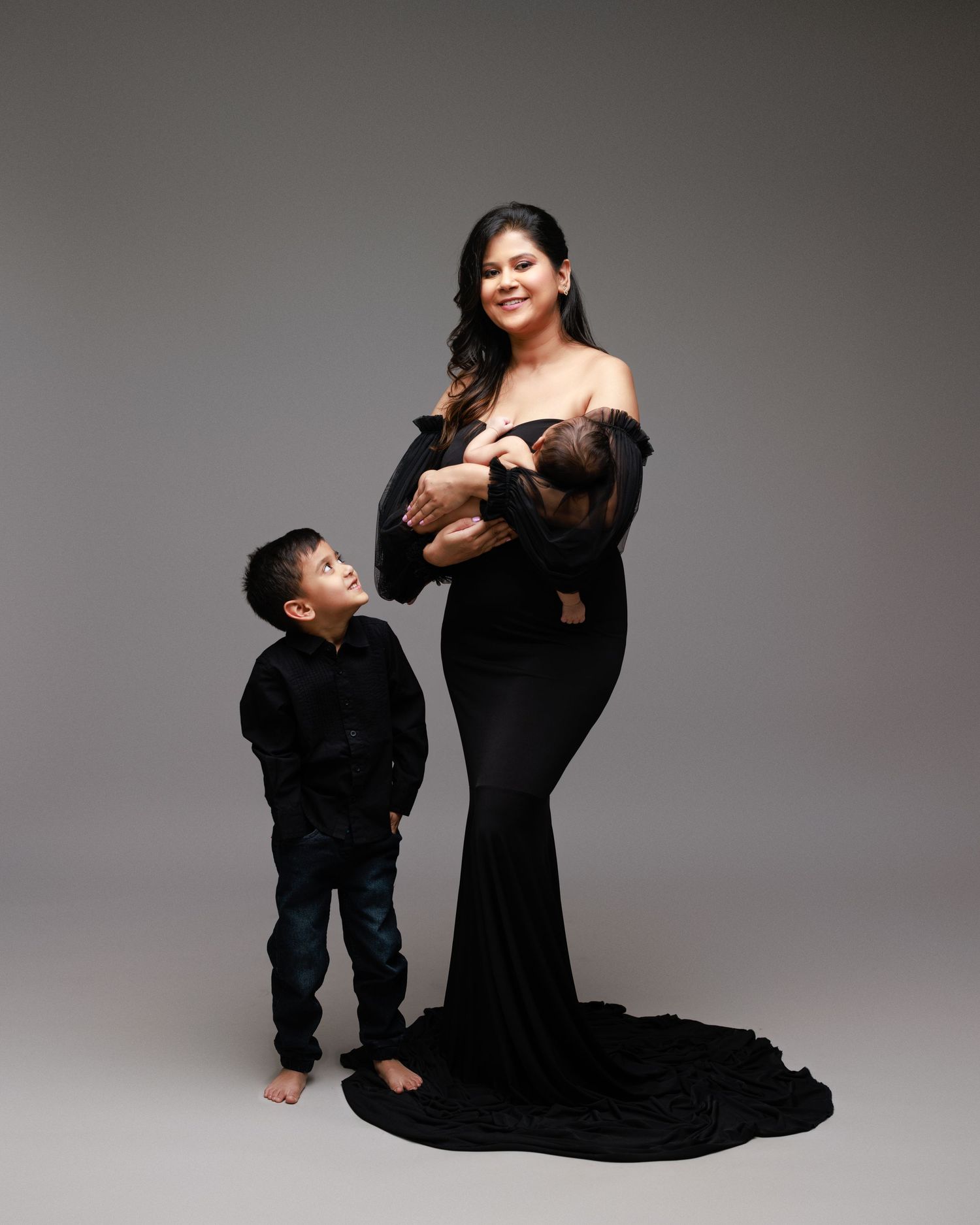 Studio portrait with elegant black dress against grey background.