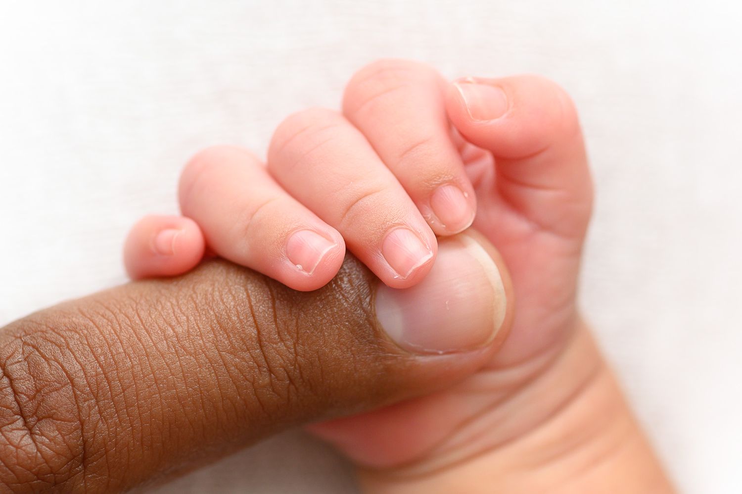 Close-up of tiny baby toes against a soft pink background.