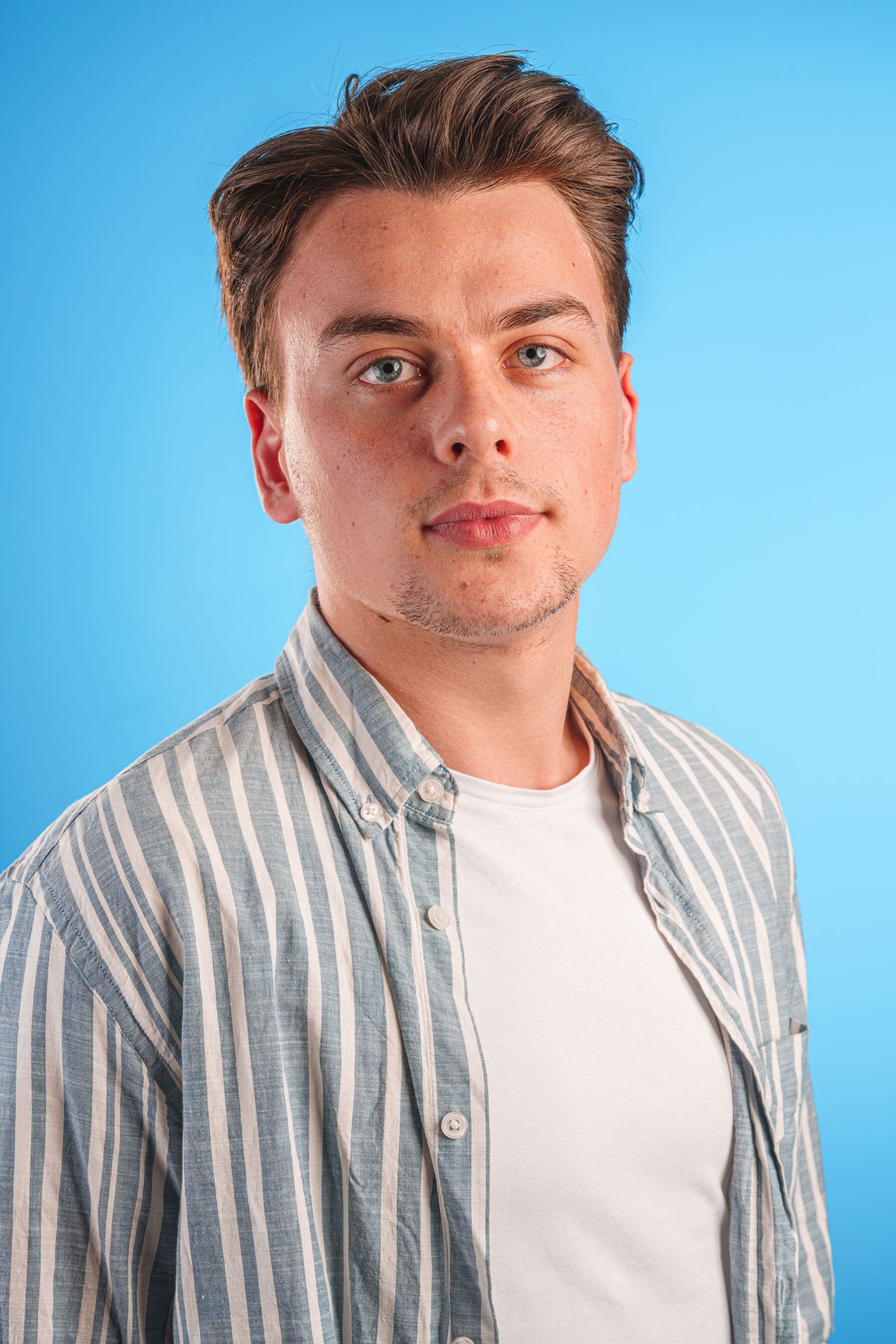 Portrait of a person in a striped shirt against a blue background.