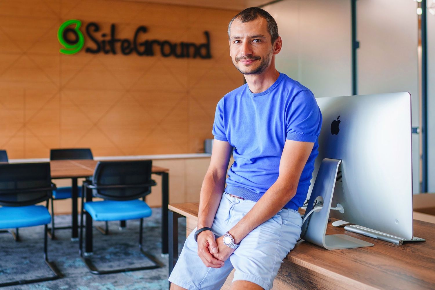 Casual office portrait of person in blue t-shirt sitting at SafeGround workplace.