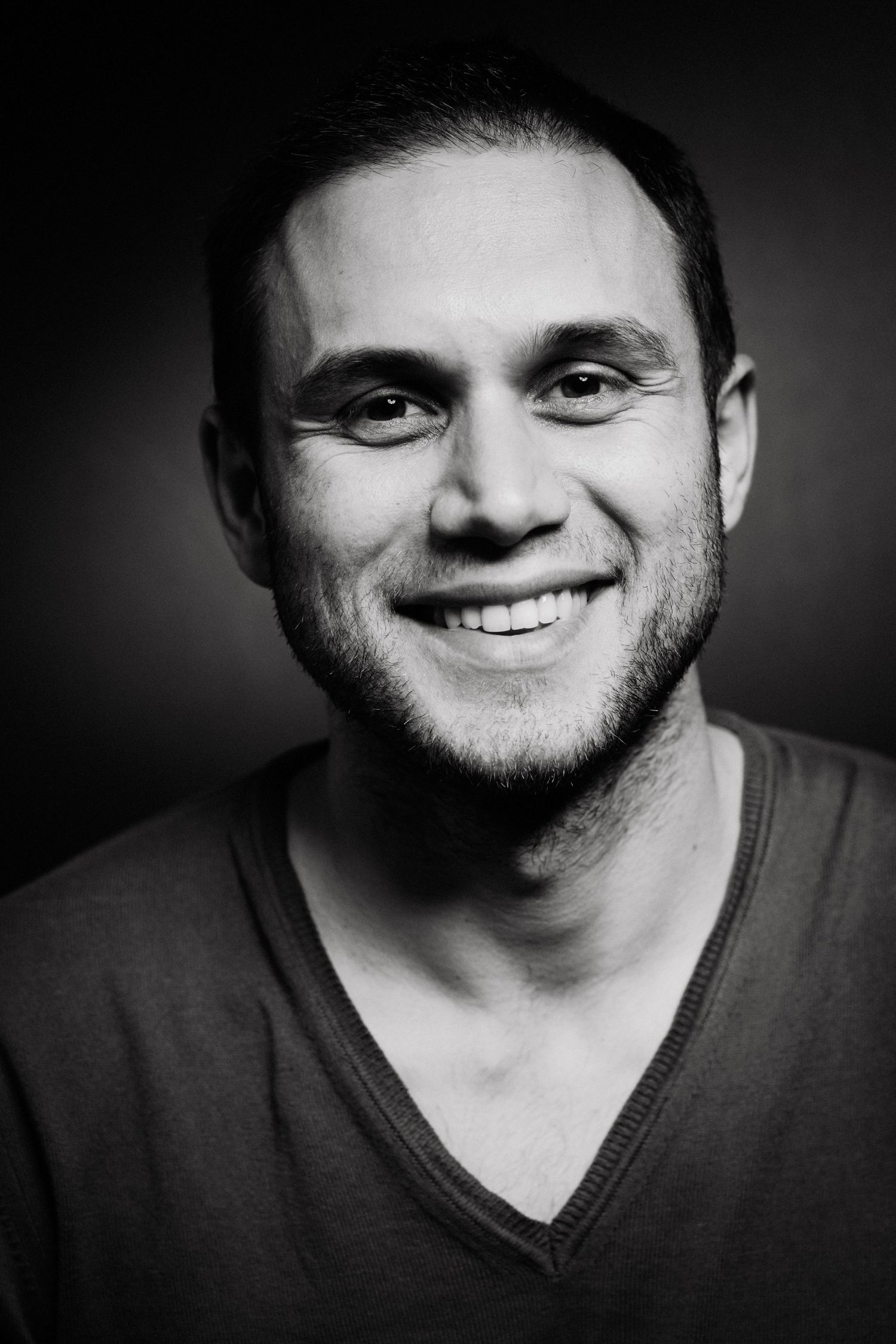 Black and white portrait of a person smiling warmly at the camera.