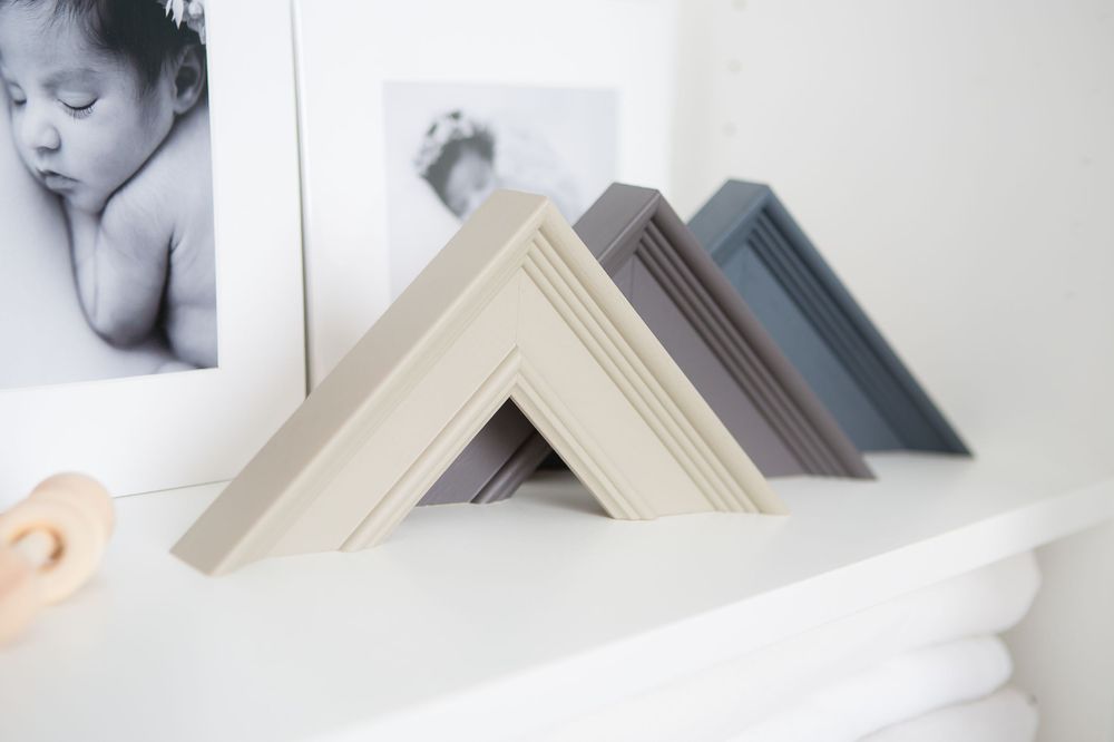 Collection of neutral-colored picture frame corners displayed on a white shelf.
