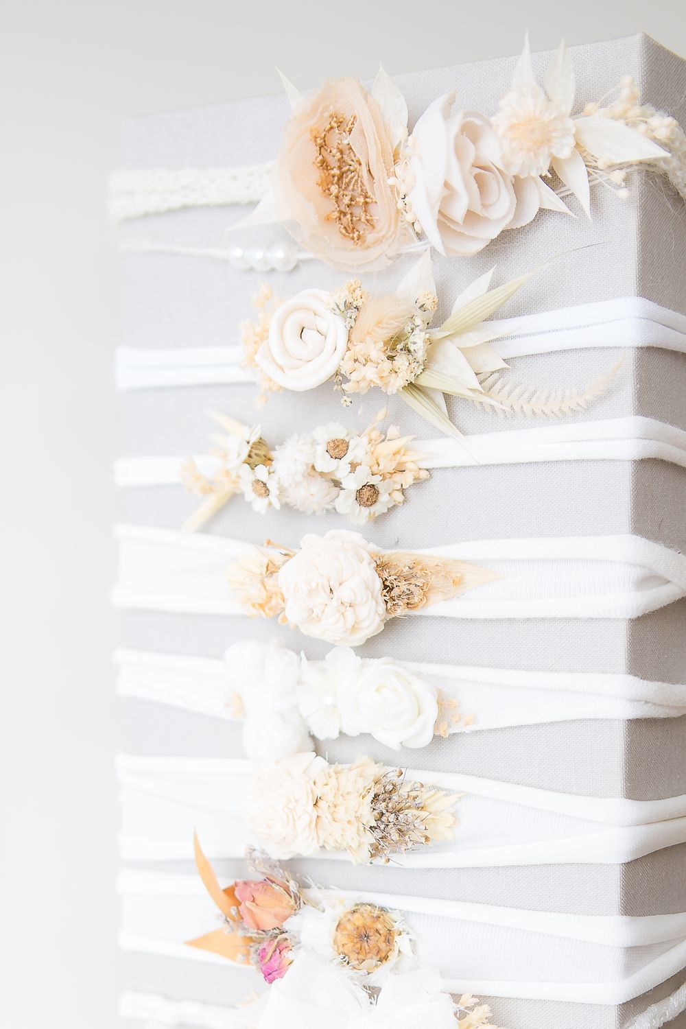 Collection of white headbands decorated with soft peach and cream floral arrangements.