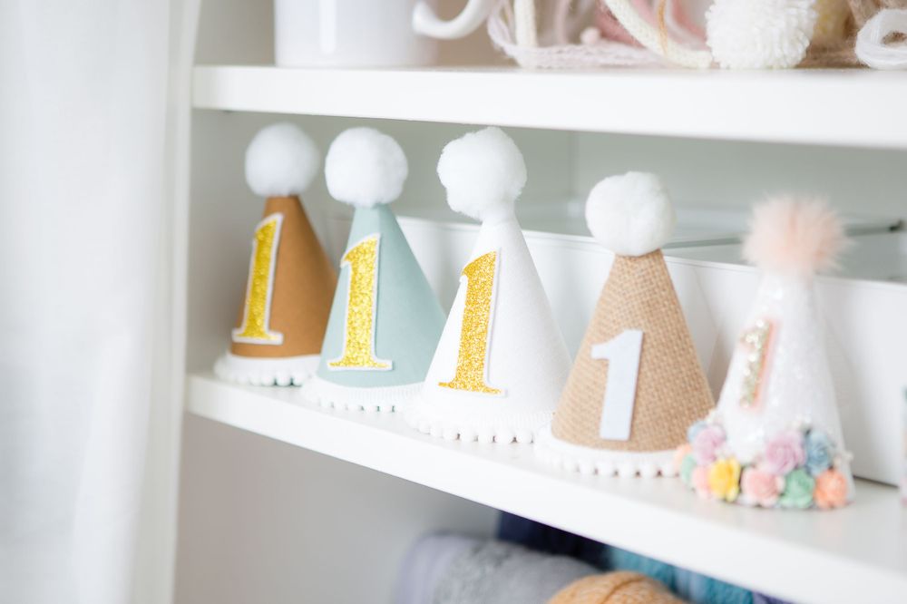 White decorative party hats with numbers displayed on a nursery shelf.