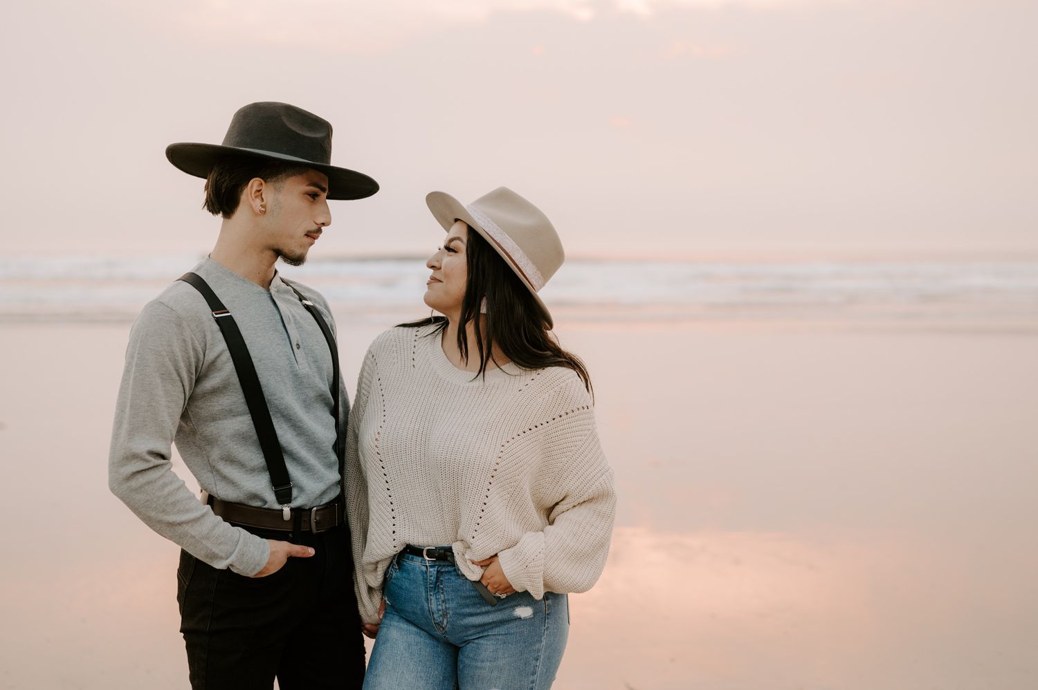 Romantic couple in vintage-inspired outfits share an intimate moment at sunset on the beach.