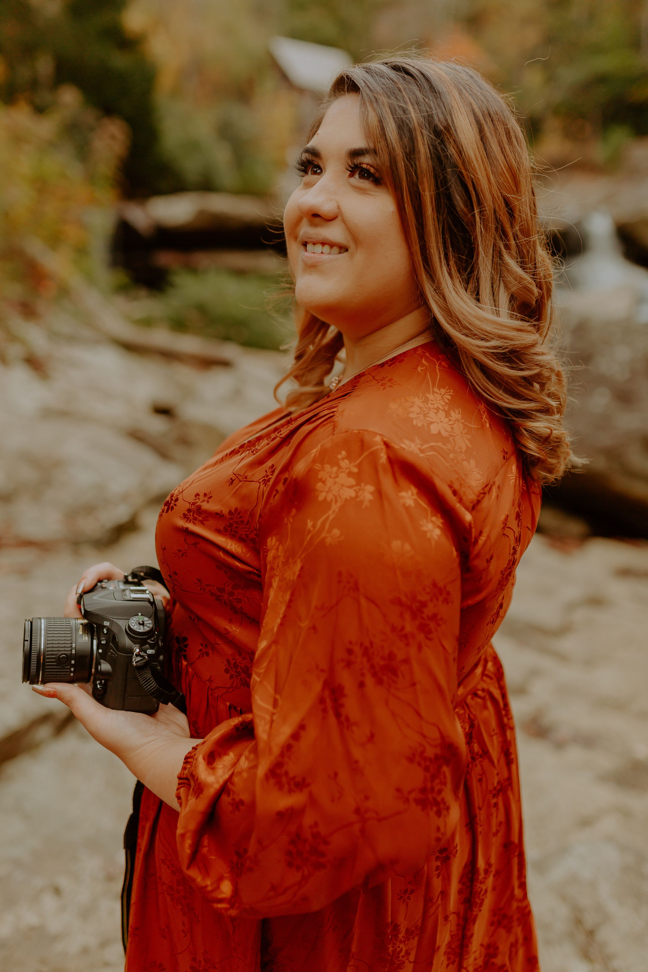 Professional photographer in an orange jacket taking photos outdoors during autumn.