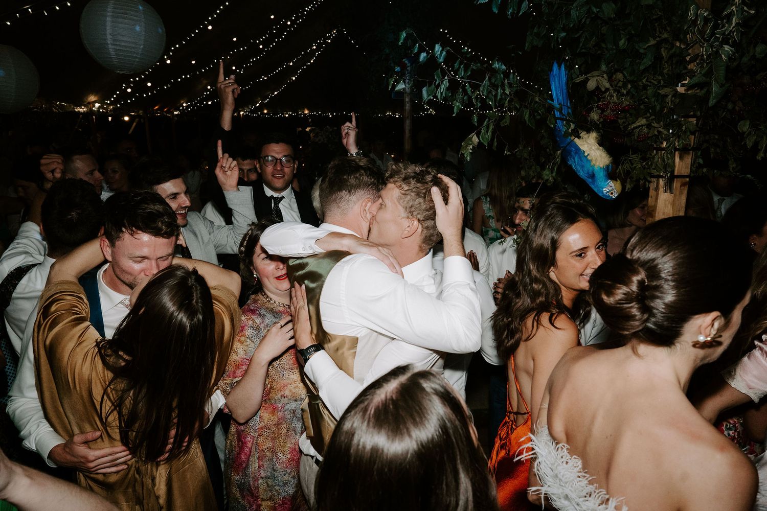 wedding guest kissing groom on cheek on a busy dance floor at wedding in oxfordshire