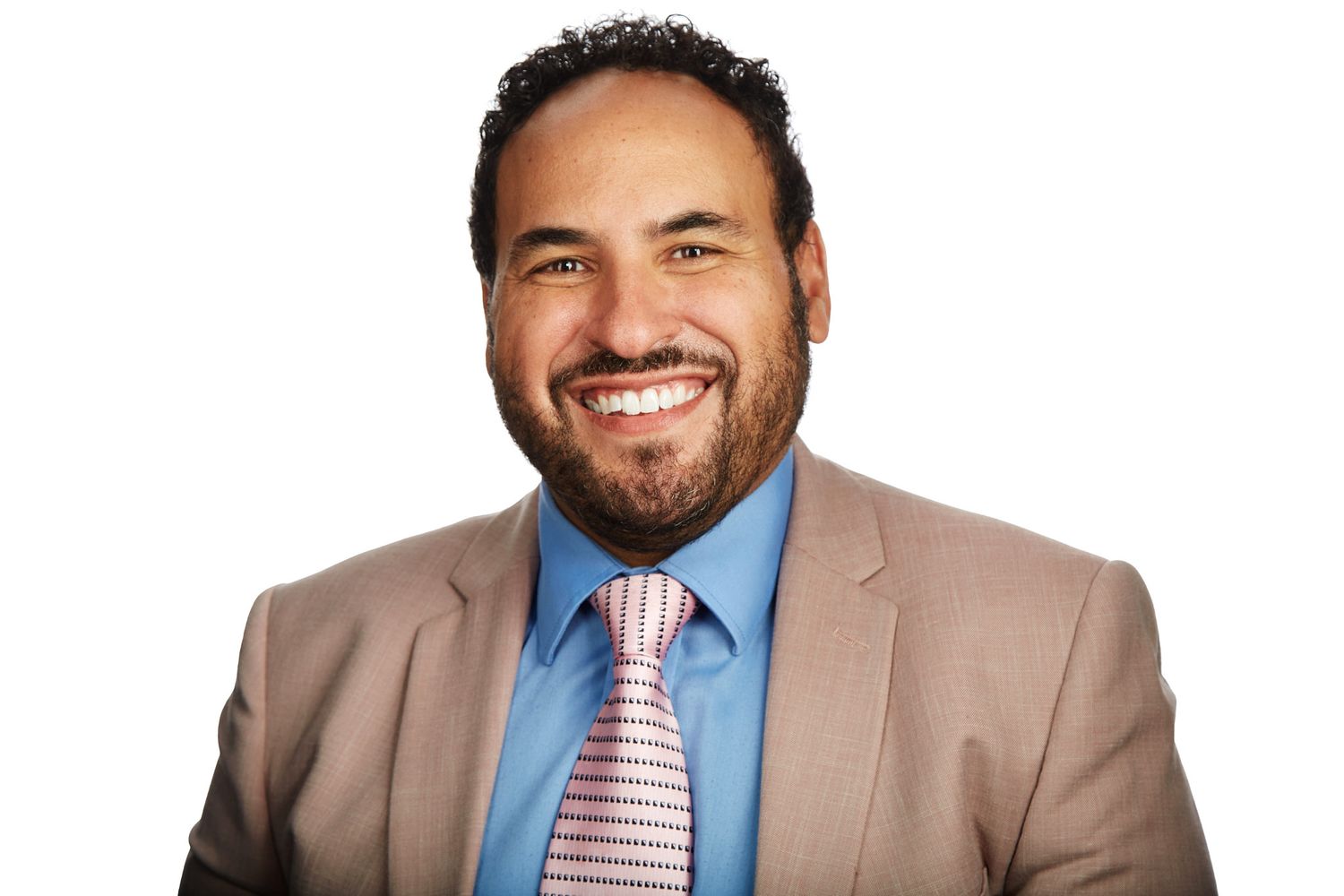 Professional headshot of a businessman in a tan suit and striped tie against white background.