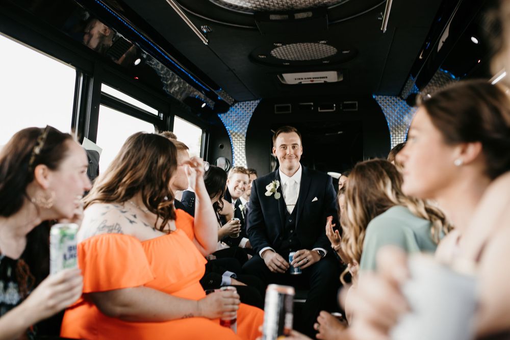 Groom surrounded by wedding party celebrating on party bus.