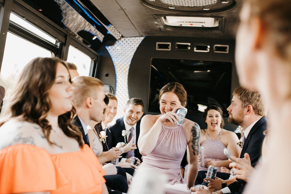 Bridesmaid drinking from can while wedding party celebrates on bus.