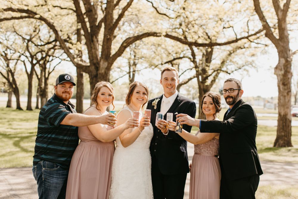 Wedding party toasting together outdoors under blooming spring trees.