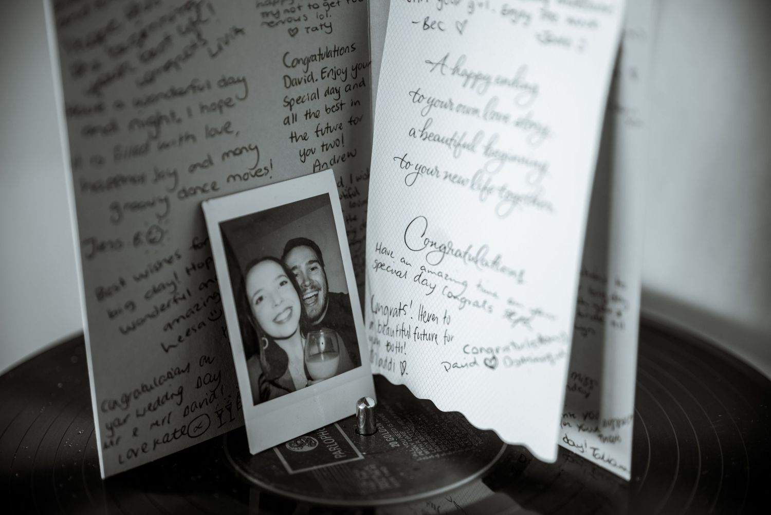 Black and white photo of a guestbook with handwritten messages and polaroid photo.