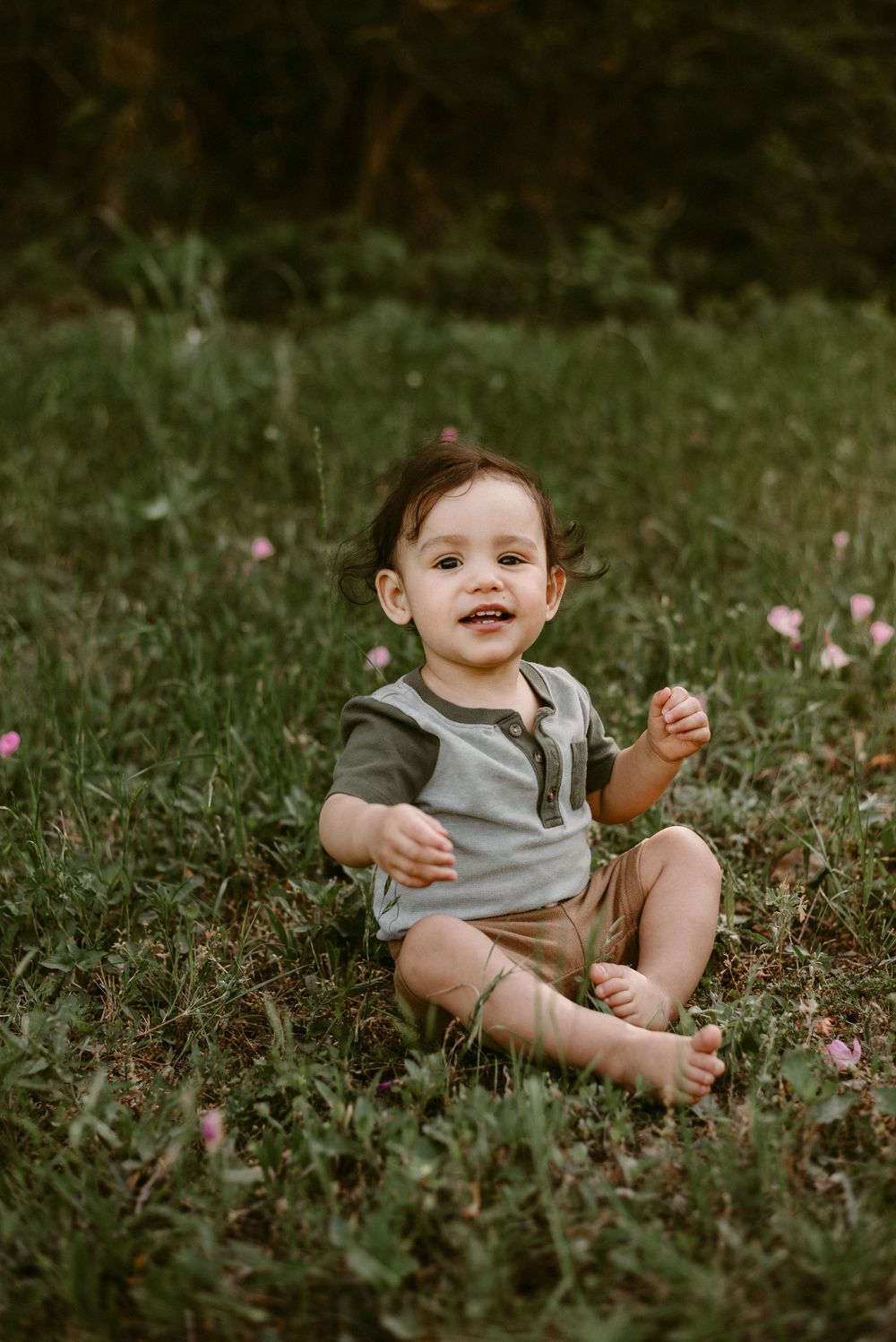 Joyful moment captured of toddler sitting in wildflower meadow wearing casual clothes.