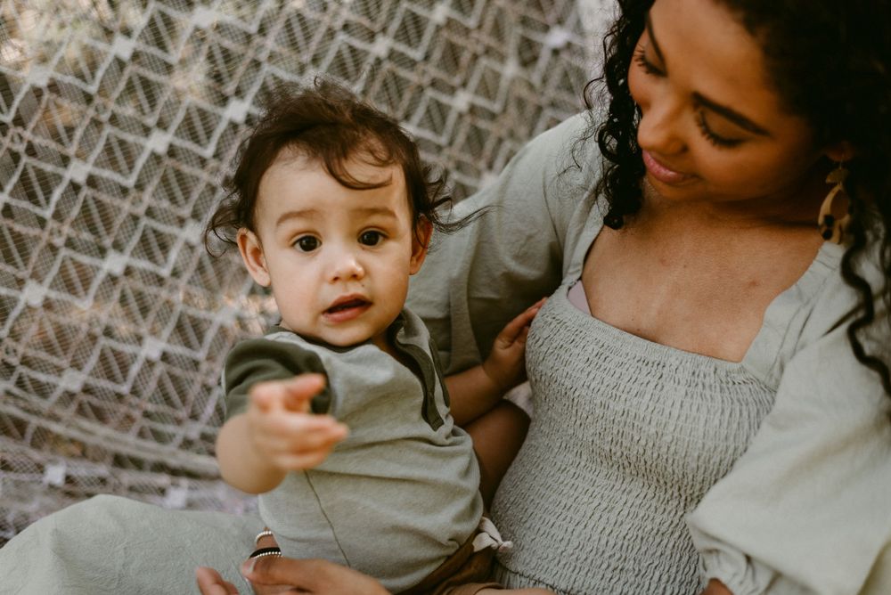 Intimate indoor portrait with textured blanket background showing tender family moment.