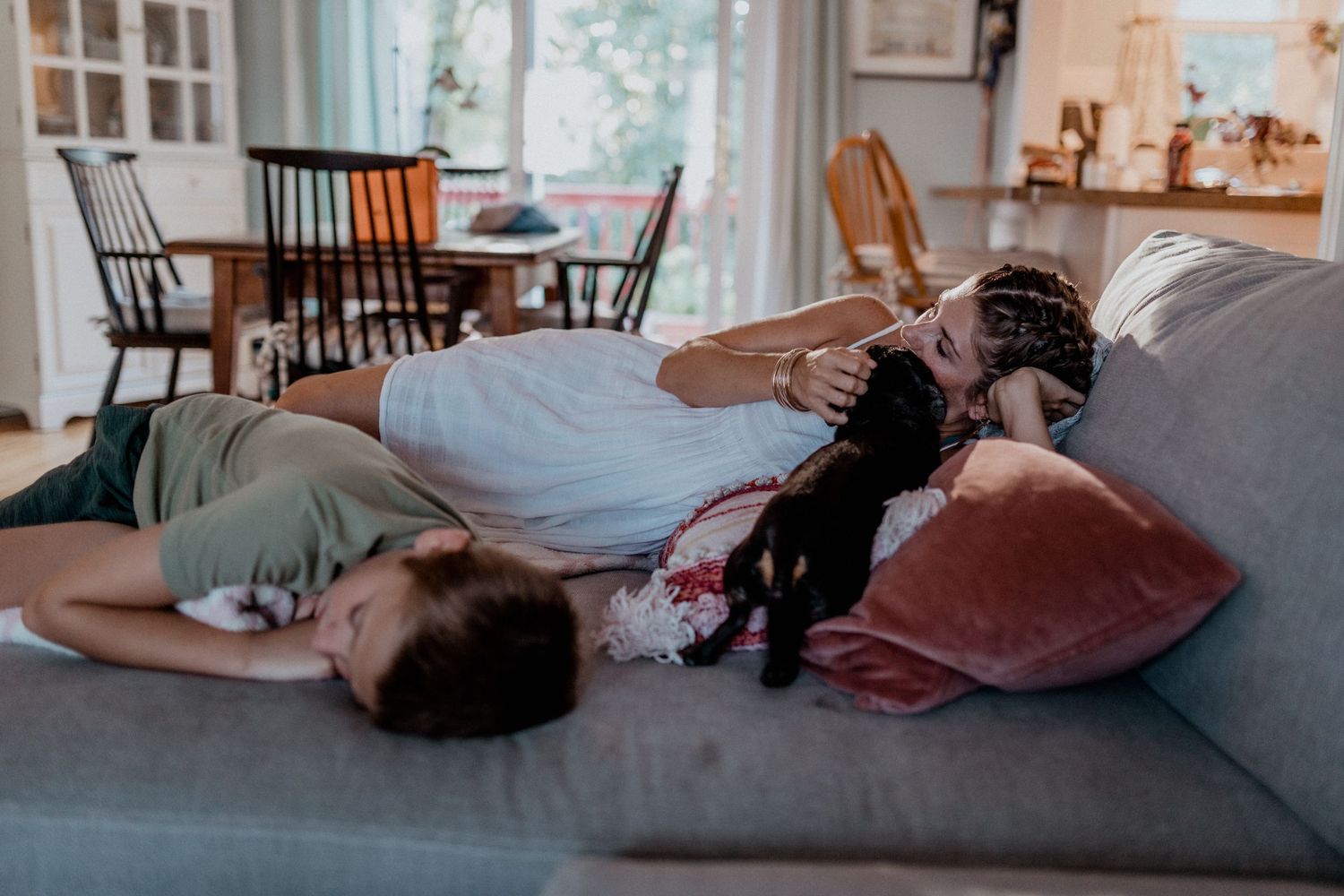 mom and son laying on their blue couch and petting the dog in their smithfield home