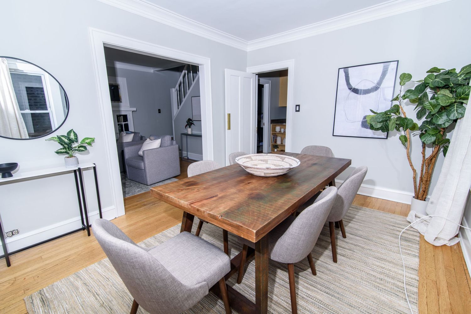 Modern dining room with wooden table, gray chairs, and minimalist wall art.
