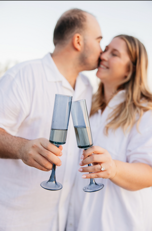 Romantic couple toasting with champagne glasses on beach.