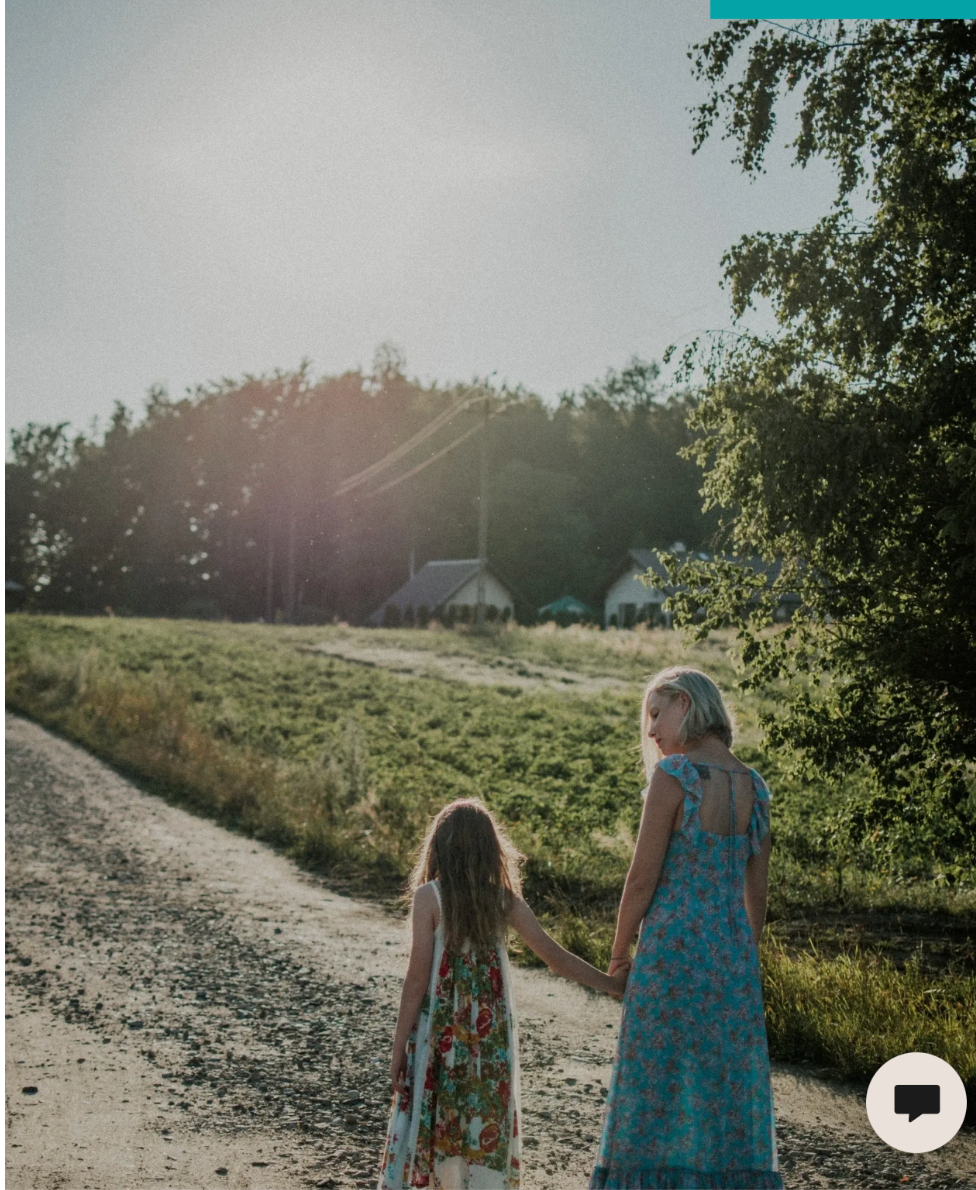 Children in matching blue dresses walking down a sunlit country path.