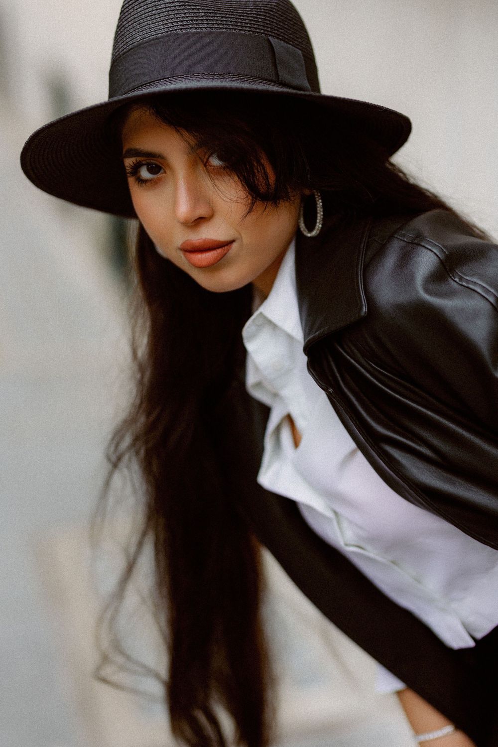 Stylish portrait featuring a black hat, white collar, and leather jacket ensemble.