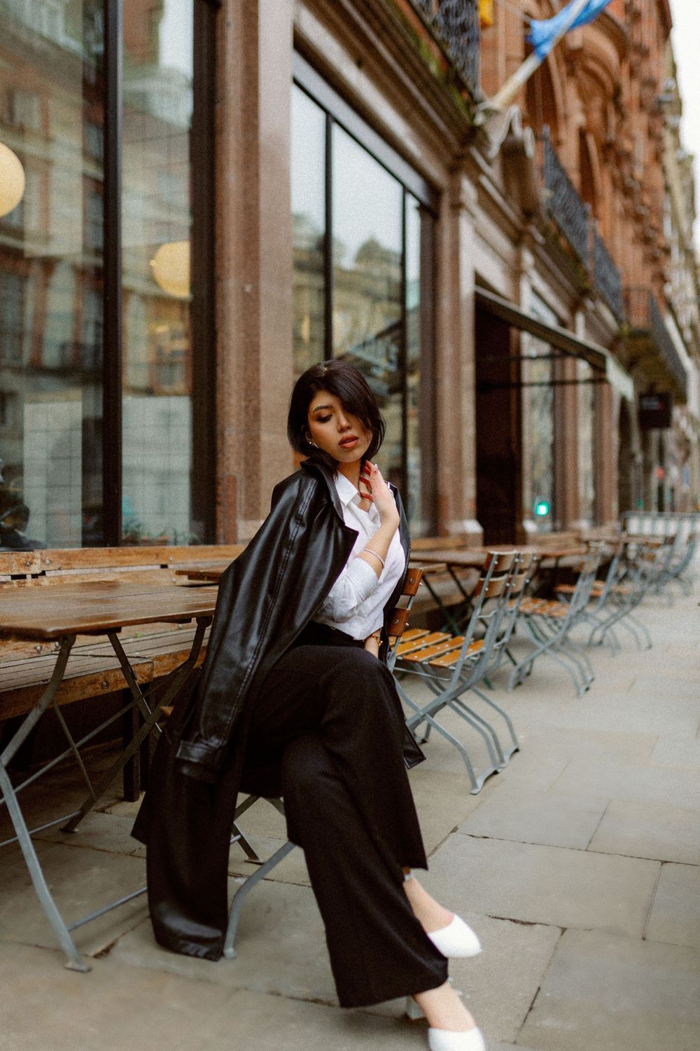Fashionable scene at a cafe terrace with metal chairs and stone architecture.