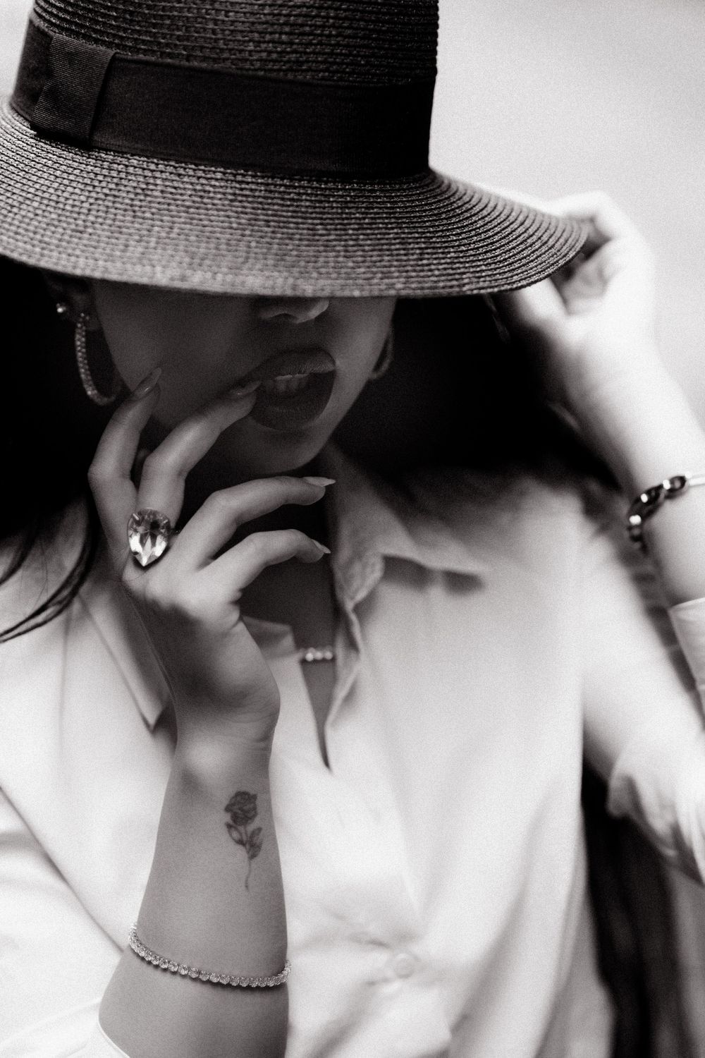 Artistic black and white portrait with a wide-brimmed hat creating dramatic shadows.