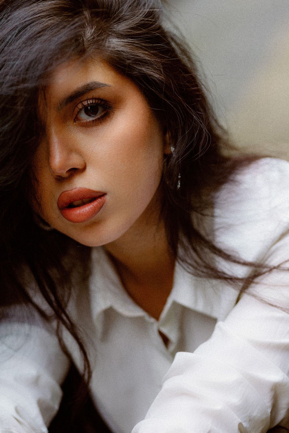 Close-up beauty shot featuring a white collared shirt and dramatic makeup.