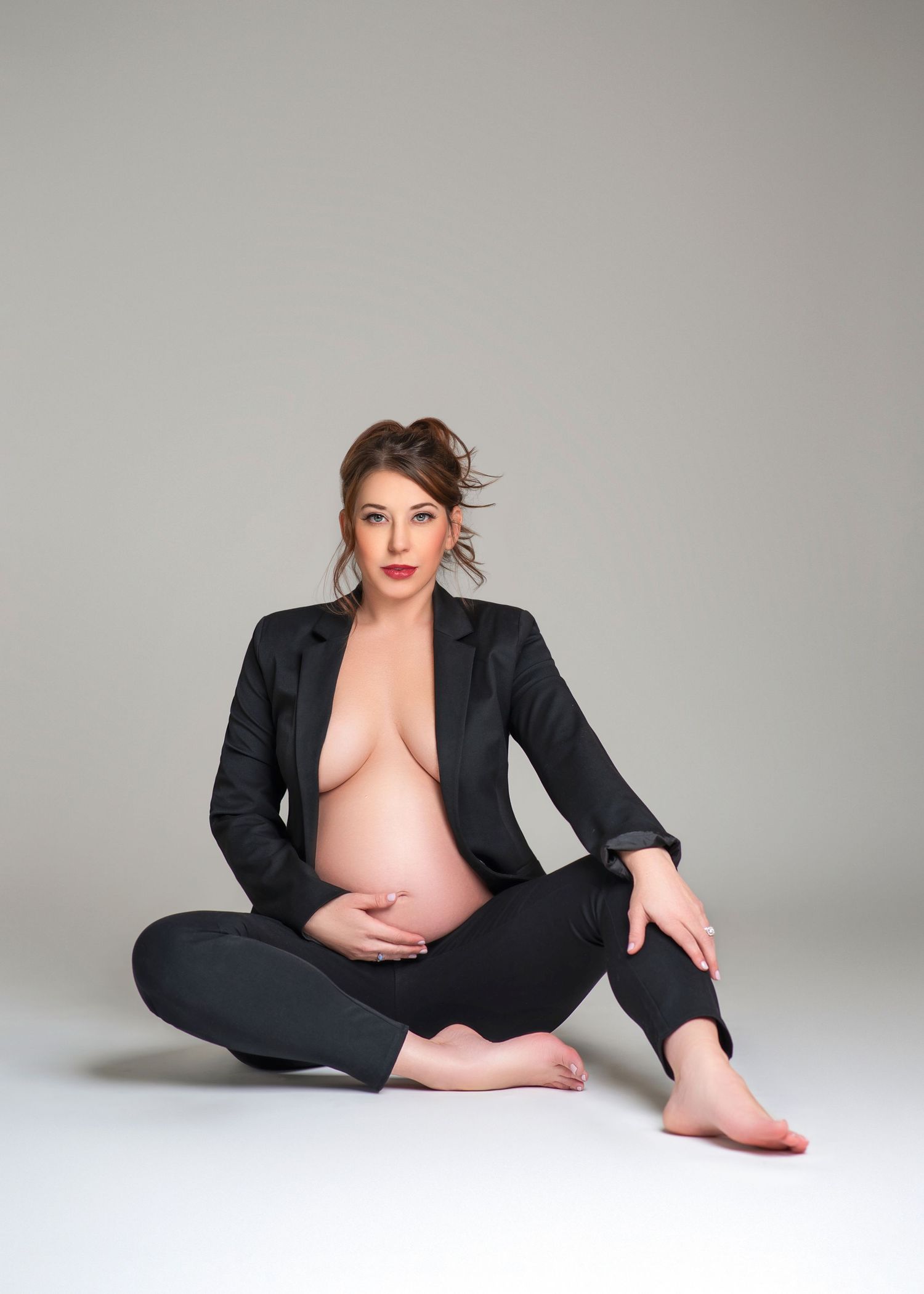 a pregnant woman looks at the camera while wearing a black blazer and pants for her maternity photography