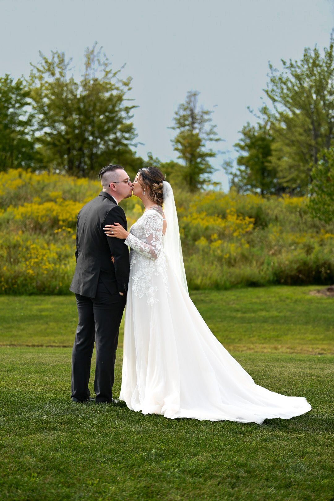 A wedding couple shares tender moments in a field of yellow wildflowers on their special day.