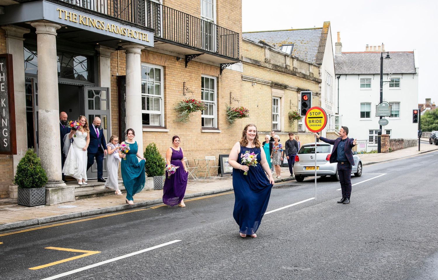 Wedding party walking along a historic stone street in formal attire.
